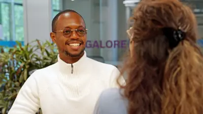 Sofoneas Getachew sits at a desk and talks to a woman.